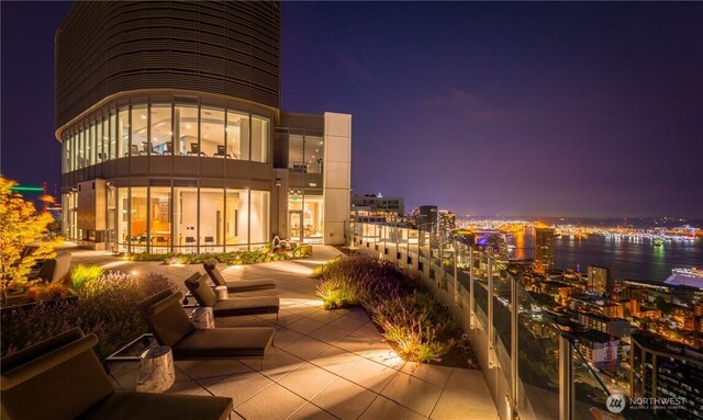 balcony at night featuring a view of city lights