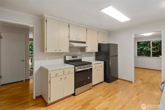 540 SW Fernwood St, Issaquah, WA 98027 - kitchen with stainless steel gas range oven, freestanding refrigerator, under cabinet range hood, light countertops, and crown molding