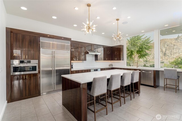 64 Orchard Pl, Orondo, WA 98843 - kitchen with under cabinet range hood, appliances with stainless steel finishes, modern cabinets, and a breakfast bar area