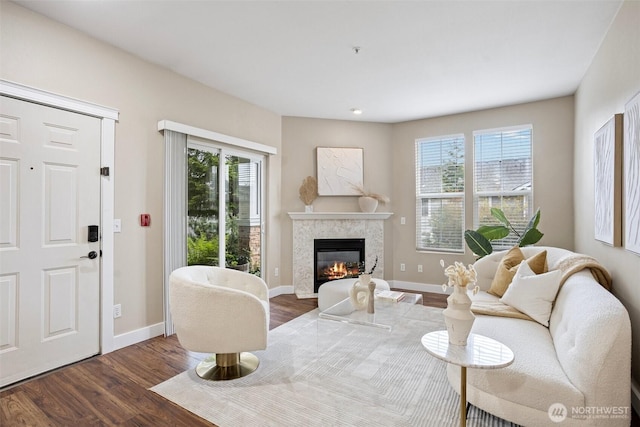 living area featuring baseboards, dark wood finished floors, and a glass covered fireplace