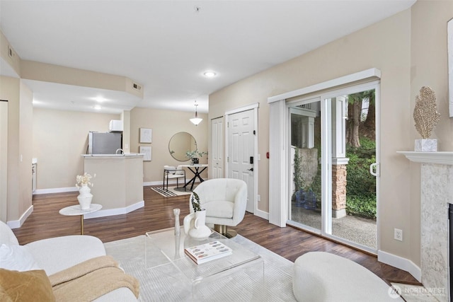 living area with baseboards, a fireplace, wood finished floors, and visible vents