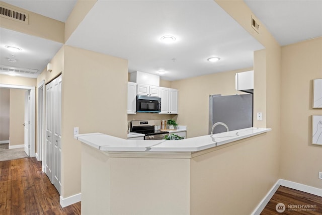 kitchen featuring visible vents, a peninsula, baseboards, dark wood-style floors, and stainless steel appliances