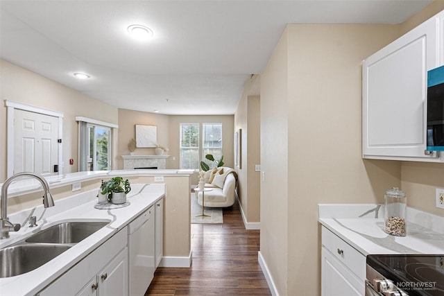 kitchen featuring a fireplace, white dishwasher, open floor plan, white cabinetry, and a sink