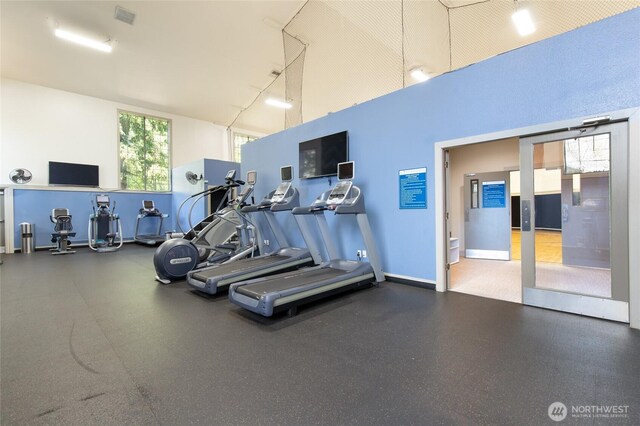 workout area featuring visible vents, baseboards, and a towering ceiling
