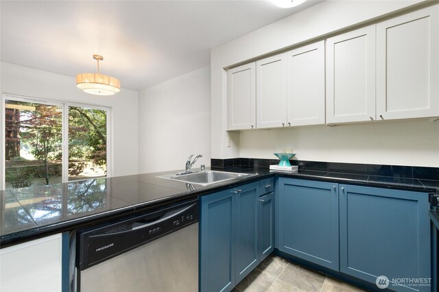 kitchen featuring stainless steel dishwasher, a peninsula, dark countertops, white cabinetry, and a sink