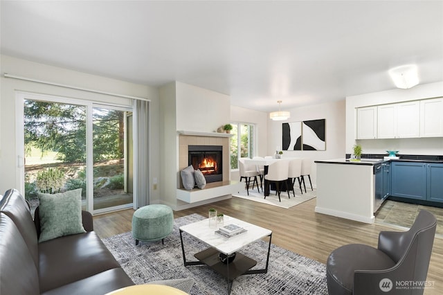 living area with baseboards, light wood-style flooring, and a tile fireplace