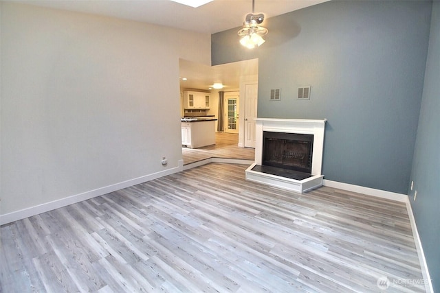 unfurnished living room featuring visible vents, a ceiling fan, baseboards, and light wood-type flooring