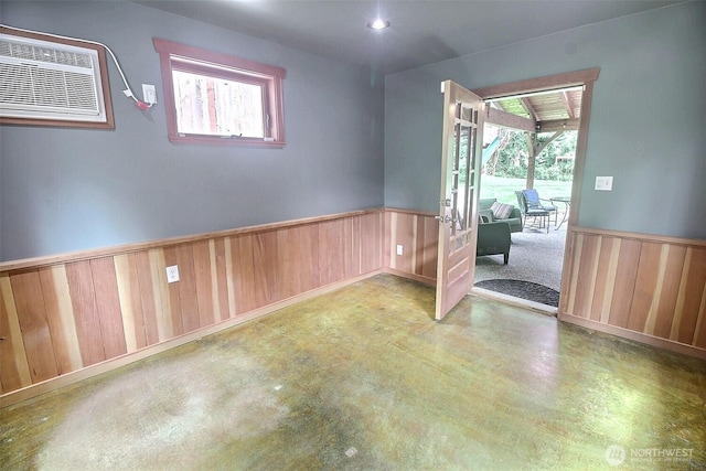 spare room featuring a wainscoted wall, concrete flooring, and a wall mounted air conditioner