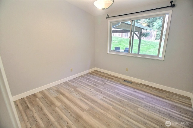 spare room featuring baseboards, light wood-type flooring, and visible vents