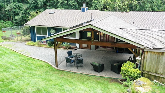back of property with a chimney, a lawn, a patio area, fence, and a shingled roof
