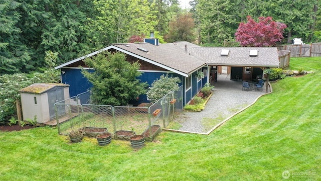 rear view of house featuring a lawn, an outbuilding, a patio area, fence, and a storage unit