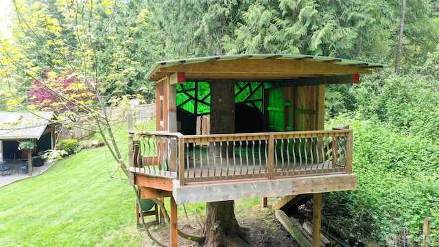 wooden deck with a view of trees, an outbuilding, and a yard