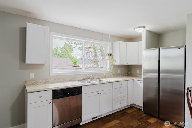 kitchen with white cabinets, appliances with stainless steel finishes, a sink, dark wood finished floors, and visible vents
