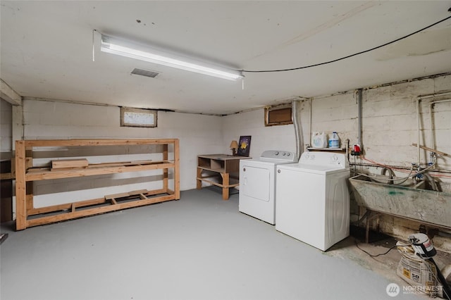 laundry room featuring laundry area, visible vents, washer and clothes dryer, a sink, and concrete block wall