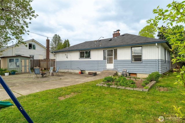 back of house featuring a chimney, a storage shed, fence, a yard, and a patio