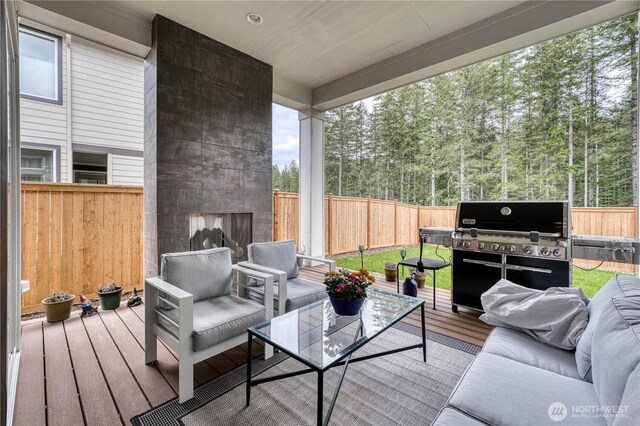 wooden deck with a fenced backyard, an outdoor living space with a fireplace, and grilling area