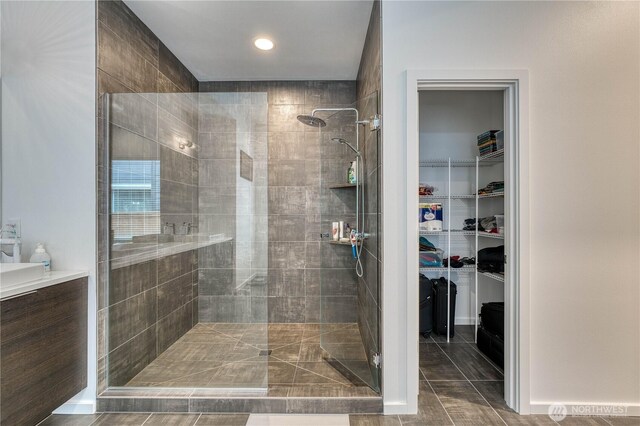 full bathroom with recessed lighting, a walk in closet, and tiled shower