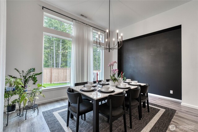 dining area with baseboards, visible vents, light wood finished floors, and a notable chandelier
