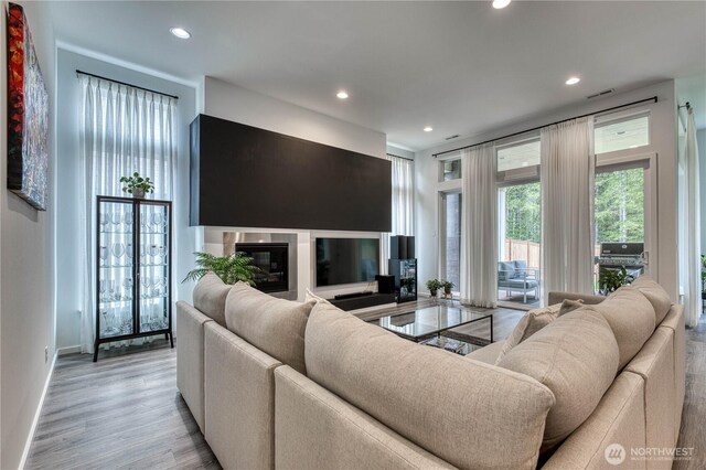 living area with baseboards, light wood finished floors, recessed lighting, and visible vents