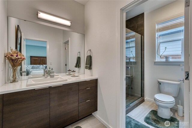 bathroom featuring vanity, baseboards, a stall shower, and toilet
