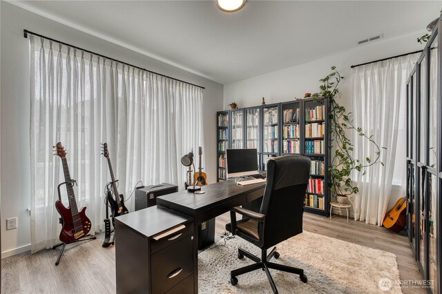 home office with baseboards, visible vents, and light wood-style flooring