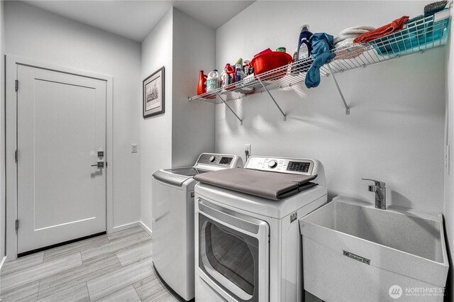 washroom featuring laundry area, a sink, baseboards, and independent washer and dryer