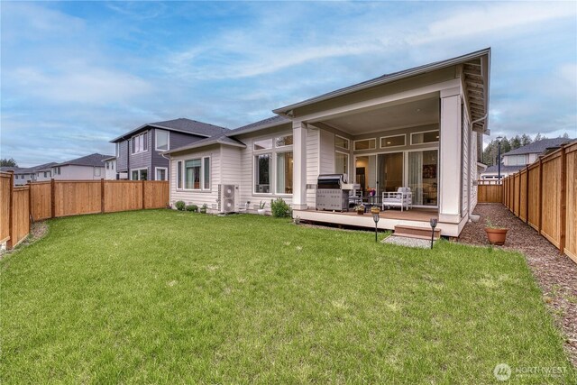 back of house with a fenced backyard, a yard, and a deck