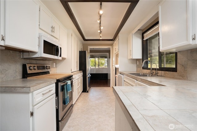 kitchen with white cabinets, stainless steel appliances, track lighting, and a sink