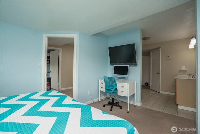 carpeted bedroom with baseboards, a sink, and tile patterned flooring