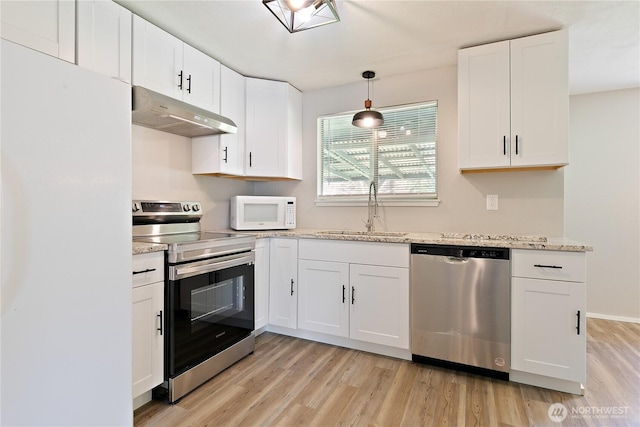 801 141st St S, Tacoma, WA 98444 - kitchen with white cabinetry, under cabinet range hood, a sink, light wood finished floors, and appliances with stainless steel finishes