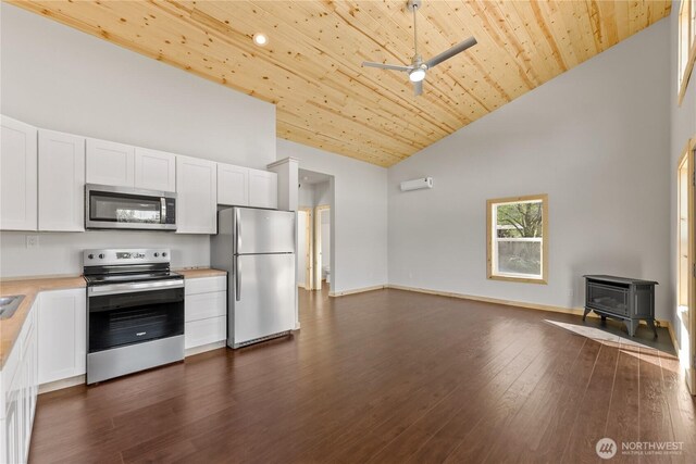 kitchen featuring a wood stove, open floor plan, high vaulted ceiling, light countertops, and appliances with stainless steel finishes