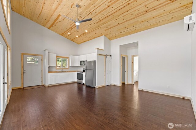 unfurnished living room with dark wood finished floors, a barn door, wooden ceiling, high vaulted ceiling, and baseboards