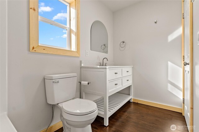 bathroom with baseboards, wood finished floors, toilet, and vanity