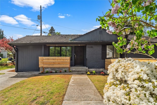 mid-century inspired home featuring brick siding, covered porch, and a front yard