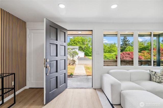 doorway to outside featuring baseboards, a healthy amount of sunlight, and light wood-style floors