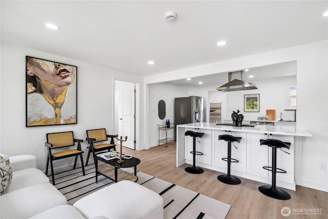 living area featuring recessed lighting, baseboards, and light wood-style flooring