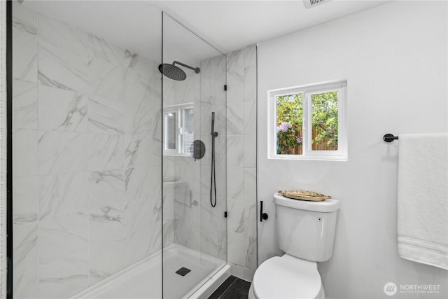 bathroom featuring a marble finish shower and toilet