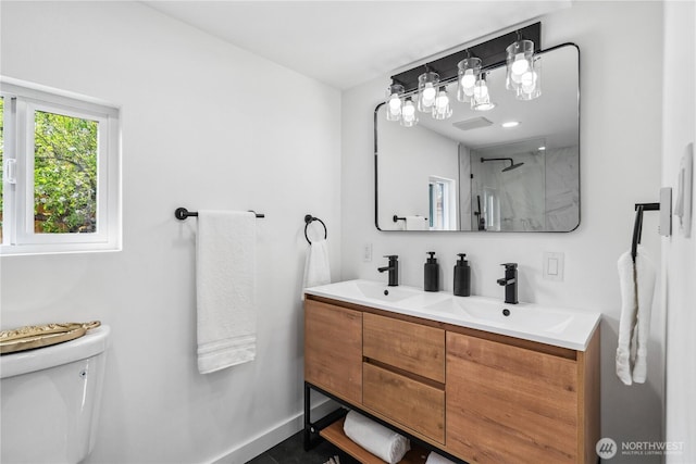 full bath featuring a sink, a shower with door, toilet, and double vanity
