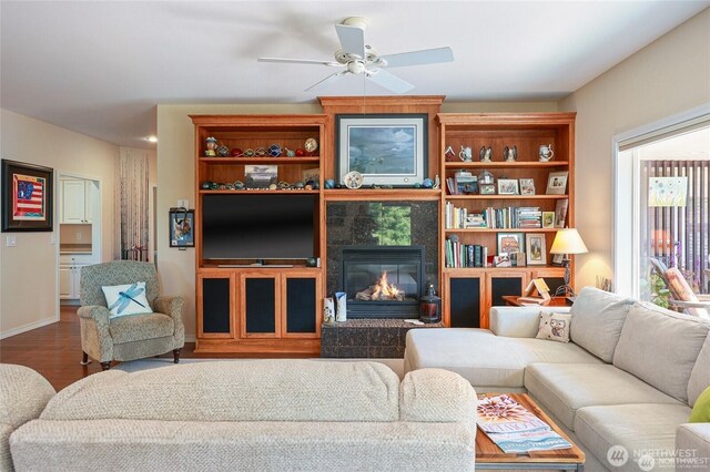living area featuring baseboards, ceiling fan, wood finished floors, and a tile fireplace