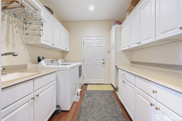 laundry area featuring independent washer and dryer, cabinet space, a sink, recessed lighting, and dark wood-type flooring