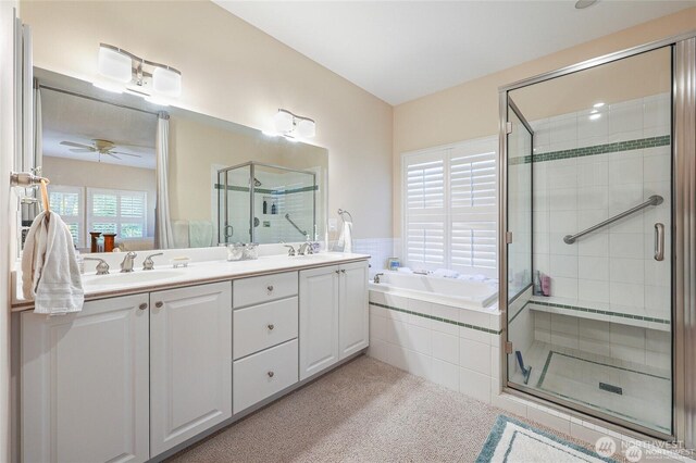 full bathroom featuring double vanity, a ceiling fan, a bath, a sink, and a stall shower