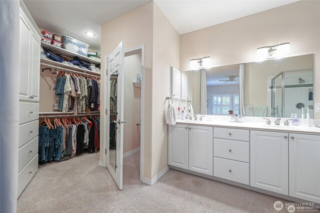 full bath featuring carpet flooring, double vanity, a spacious closet, and a stall shower