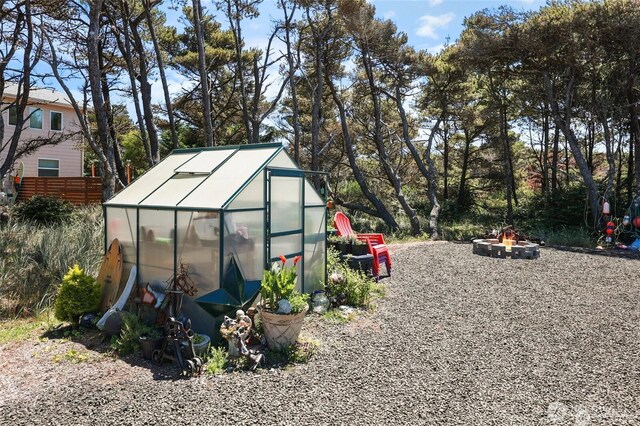 view of greenhouse with fence and an outdoor fire pit