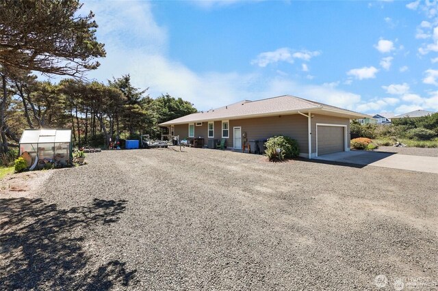 view of front facade with a garage, a greenhouse, and driveway