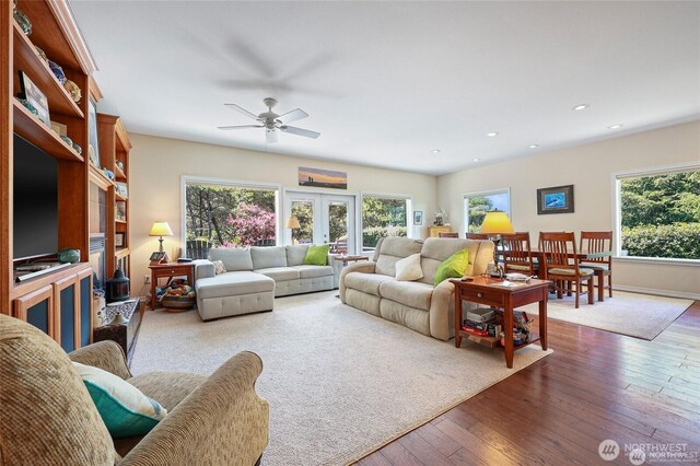 living area with wood-type flooring, ceiling fan, and plenty of natural light