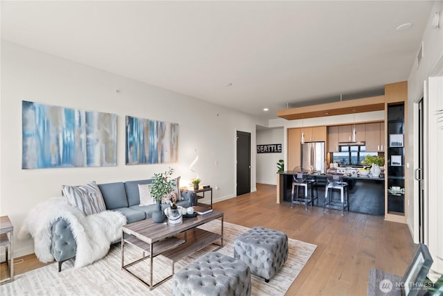 living area with baseboards, recessed lighting, and light wood-style flooring