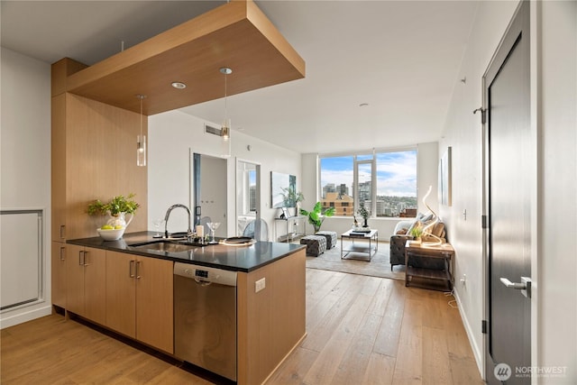 kitchen featuring dark countertops, a sink, dishwasher, a peninsula, and open floor plan
