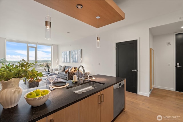kitchen with pendant lighting, dishwasher, a sink, light wood finished floors, and open floor plan