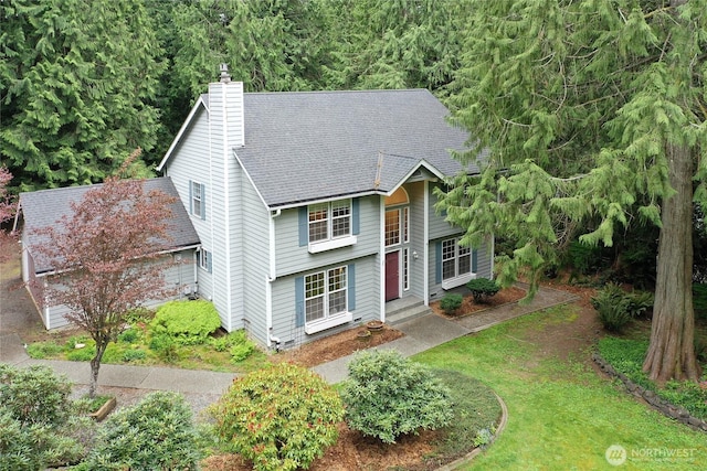 bi-level home featuring a shingled roof and a chimney