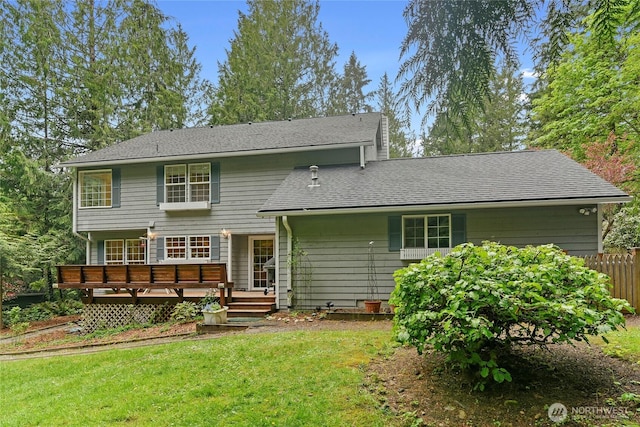 rear view of house with roof with shingles, fence, a yard, and a deck
